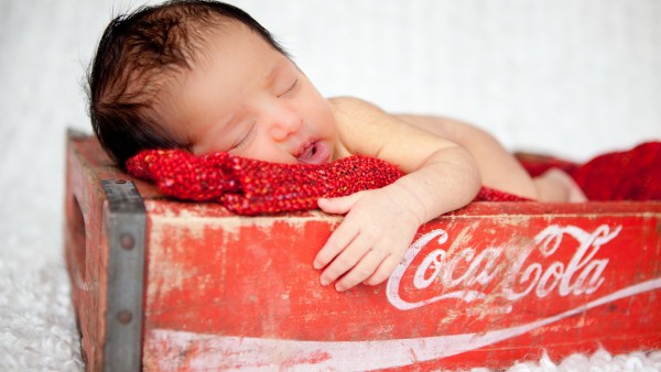 Маленький ребенок спит на бренде Кока-Кола