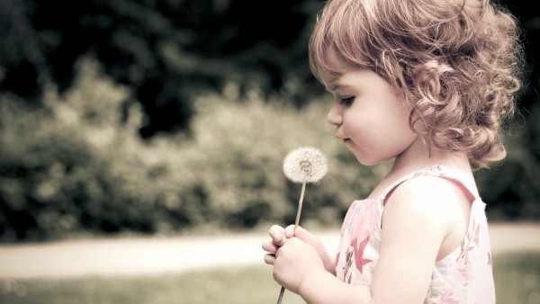 Маленькая девочка с одуванчиком в руках