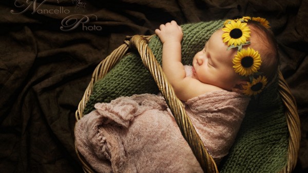 Спящий ребенок с венком из подсолнухов на голове 