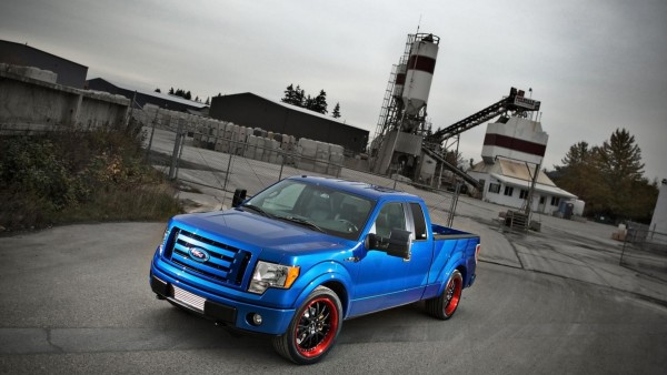 Фото синего автомобиля марки Ford стоящего около какой-то фабрики